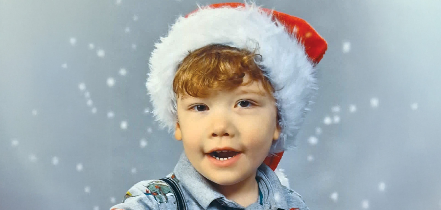 Teddie smiling whilst wearing a Santa hat.
