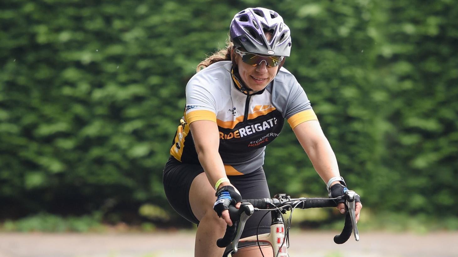 Cyclist smiling with helmet and reflective glasses in from on green lush hedge