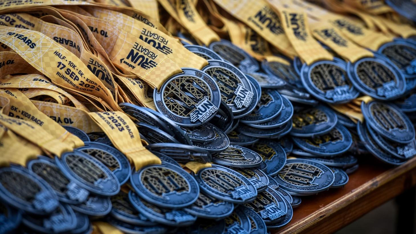 blue medals on cream printed lanyards piled up on a table