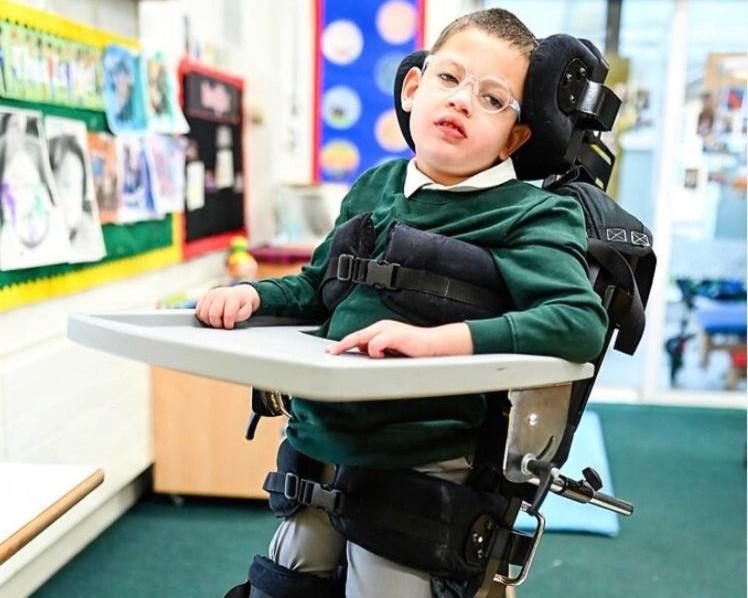 Seb in his school uniform in a standing frame