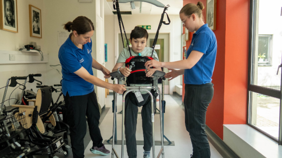 Leo in a therapy session using the Guldmann Hoist with therapists