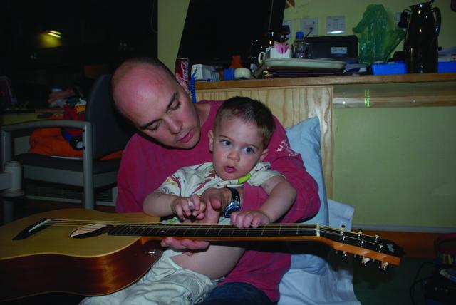 Tommy with family holding a guitar