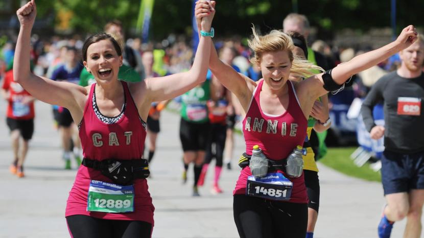 Two marathon runners holding hands celebrating 